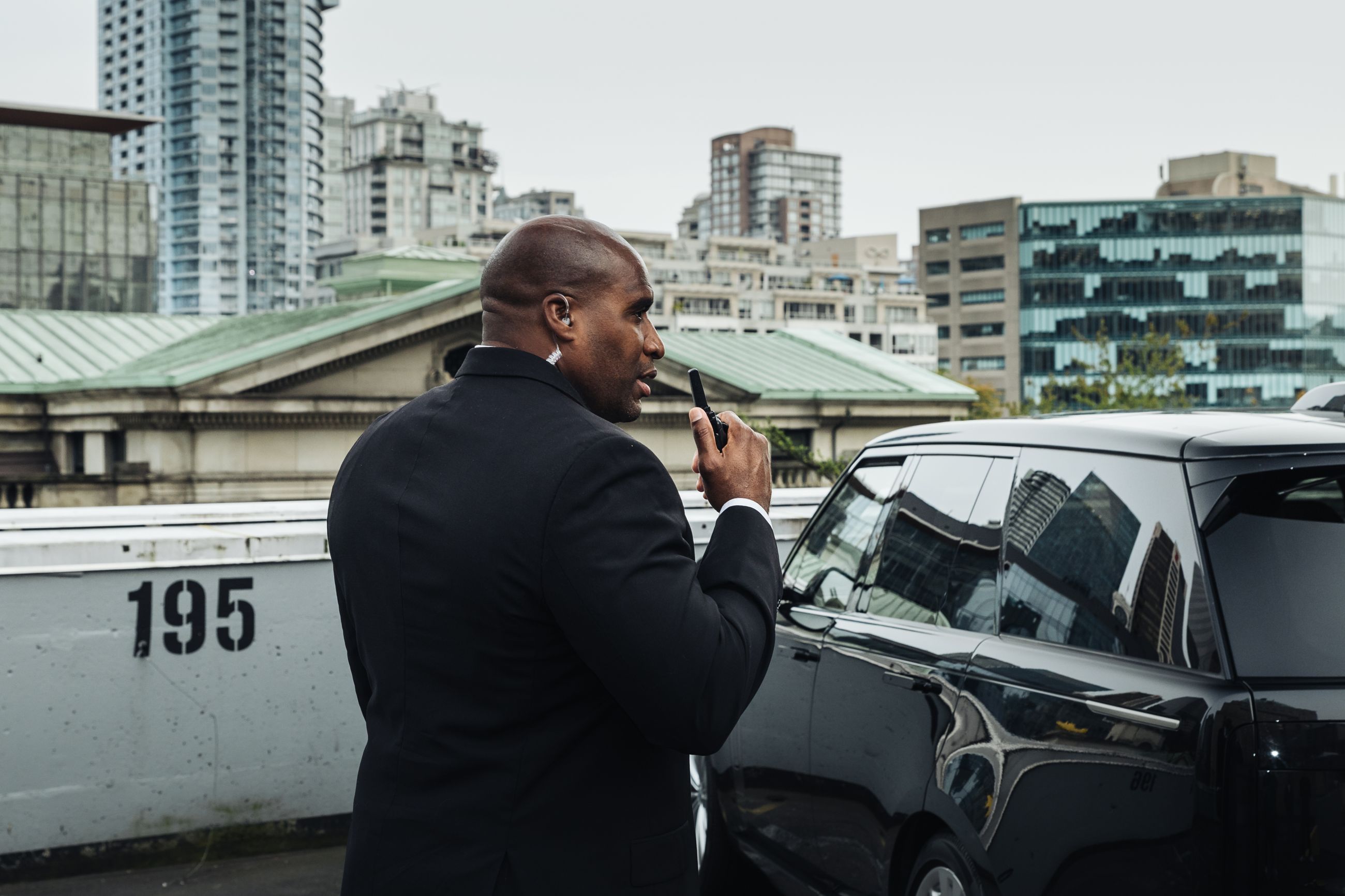 MI8 officer on the radio beside a Range Rover